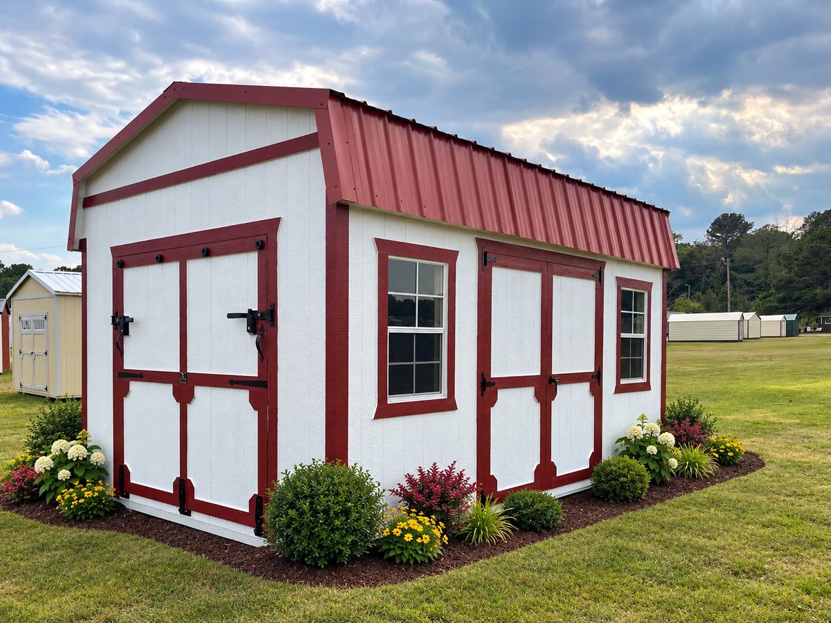12×16 Lofted Barn with Ramp Door: White with red trim and red metal roof. Ramp door closed on the end, double doors on the side.