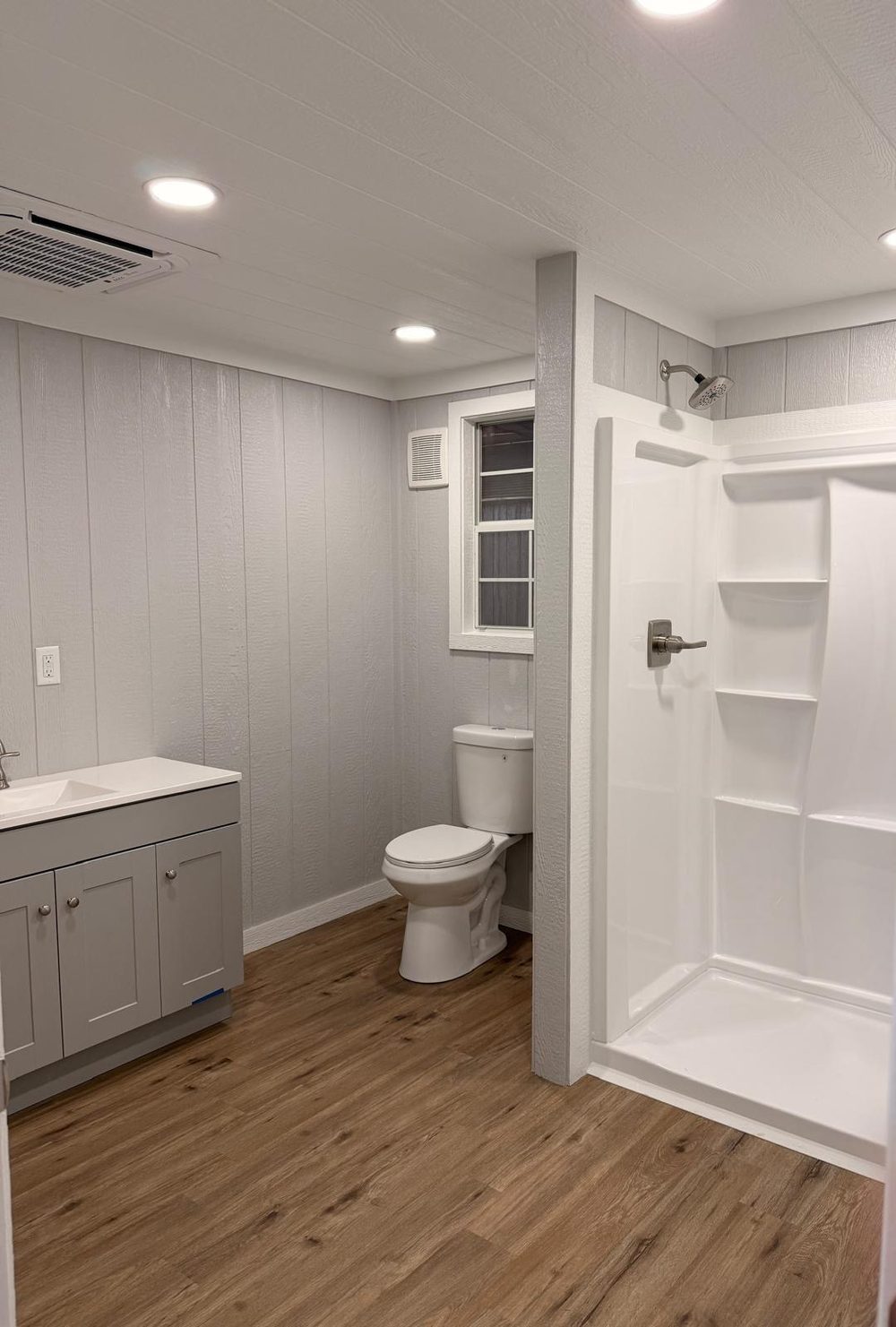 Bathroom vanity and shower with ductless air conditioner on the ceiling