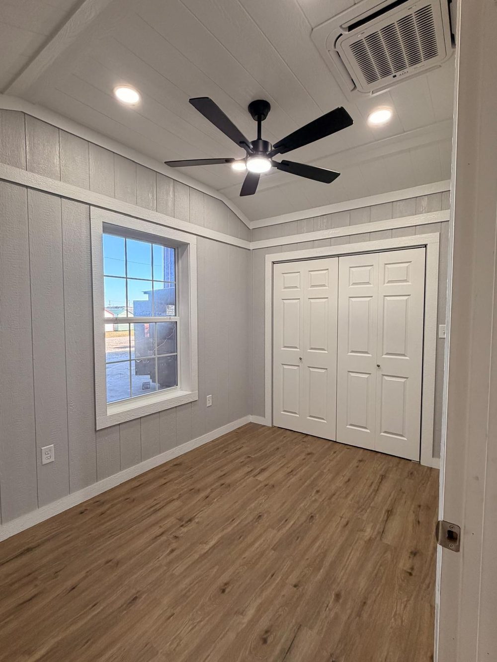 Bedroom with large window, ceiling fan and bifold closet doors
